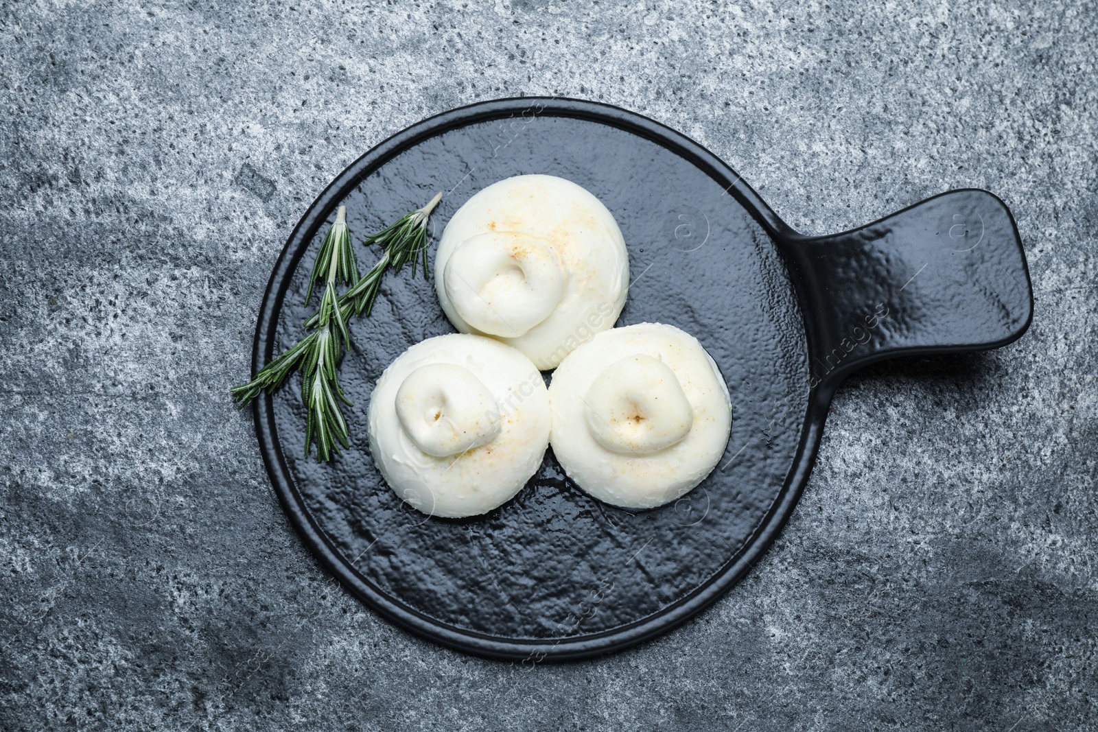 Photo of Delicious burrata cheese with rosemary on grey table, top view