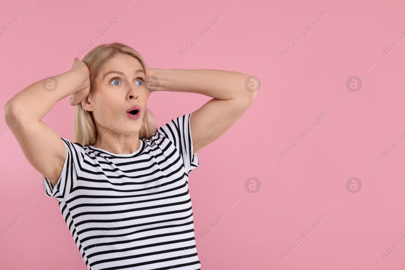 Photo of Portrait of surprised woman on pink background, space for text