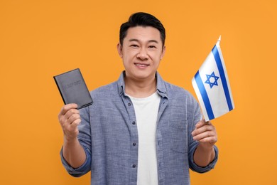 Photo of Immigration. Happy man with passport and flag of Israel on orange background