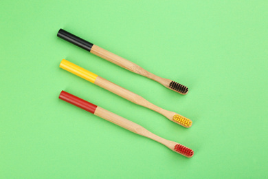 Photo of Natural bamboo toothbrushes on green background, flat lay