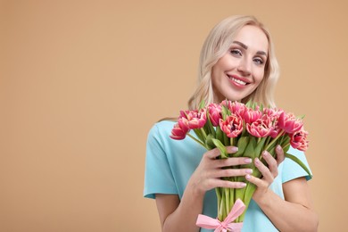 Photo of Happy young woman with beautiful bouquet on beige background. Space for text