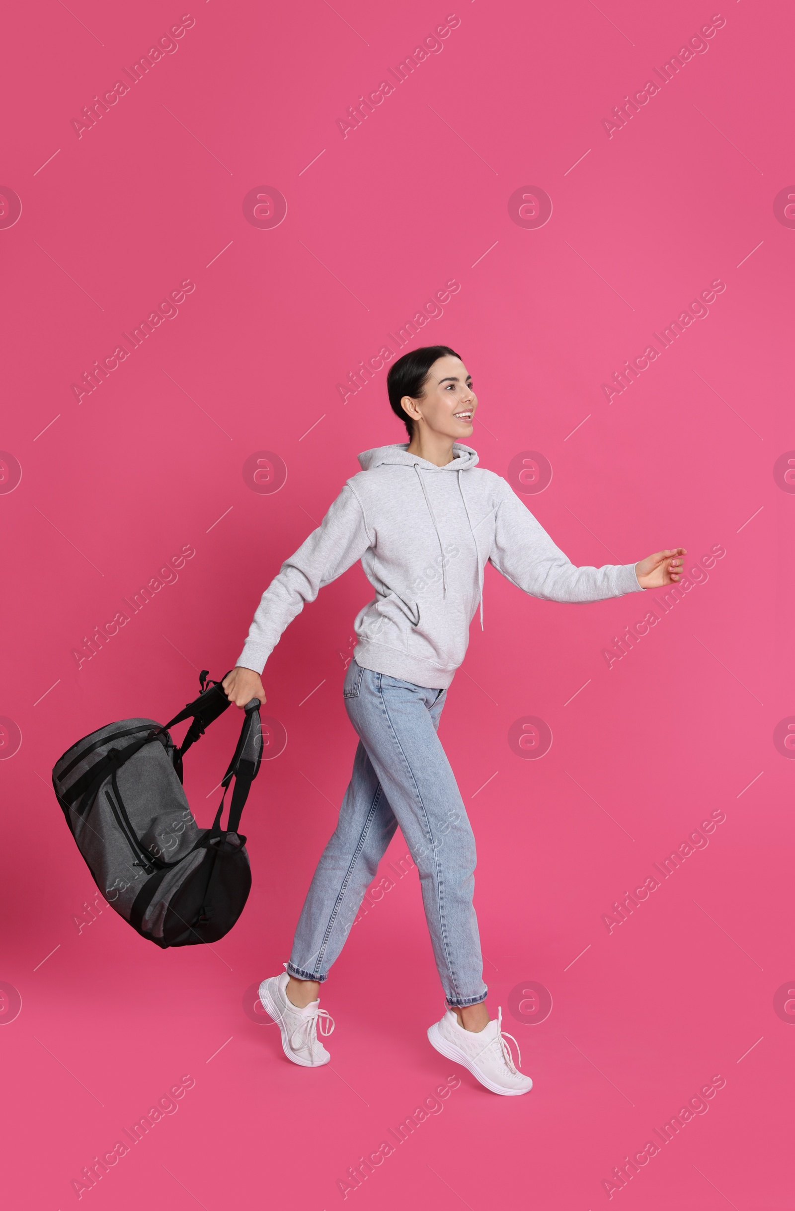 Photo of Beautiful woman with sports bag on pink background