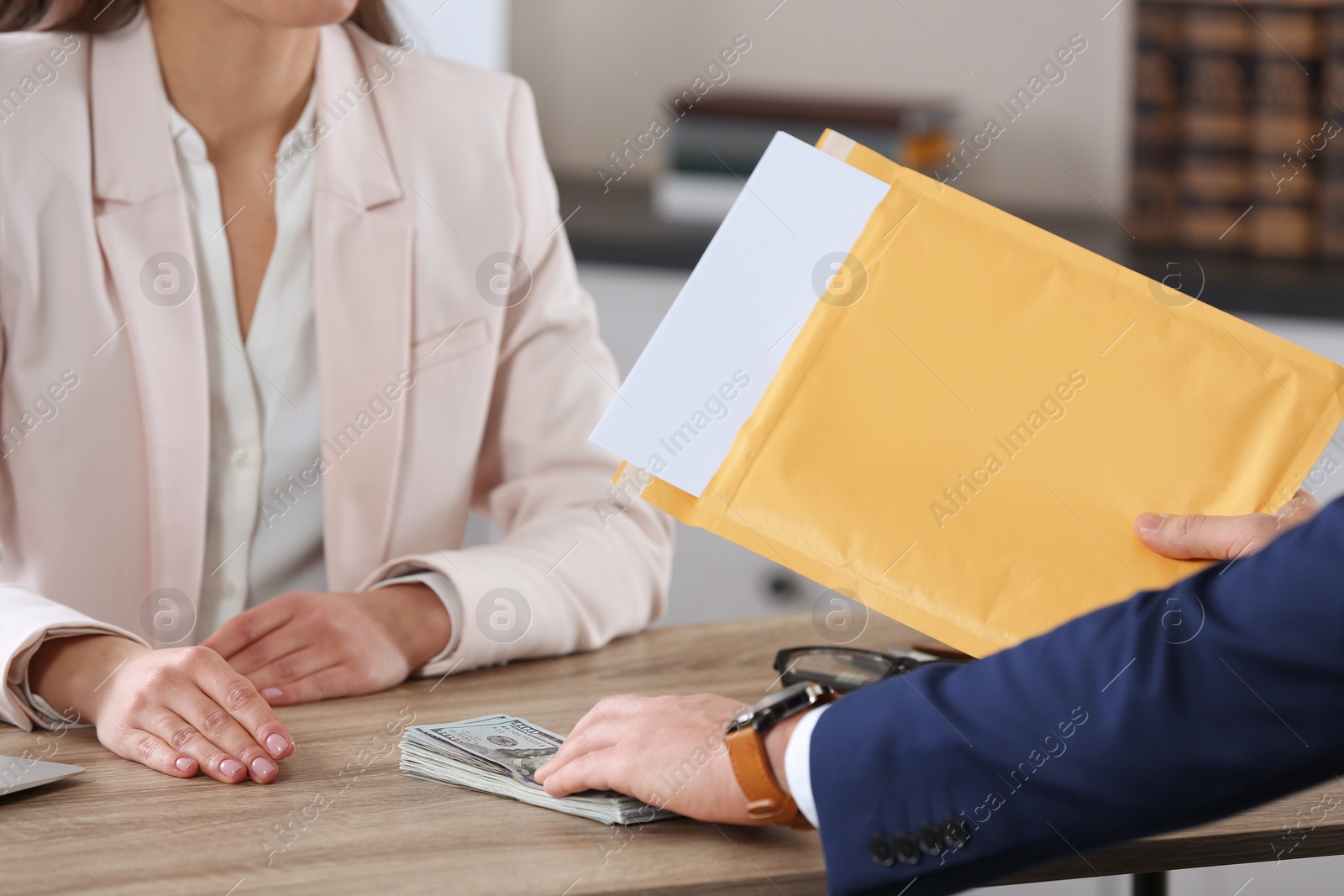 Photo of Man offering bribe to woman at table in office, closeup