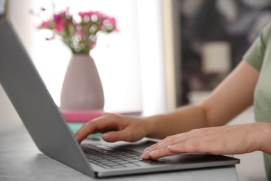 Photo of Woman working with modern laptop at light table, closeup