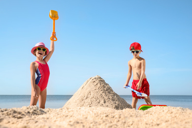 Cute little children playing with plastic toys on sandy beach