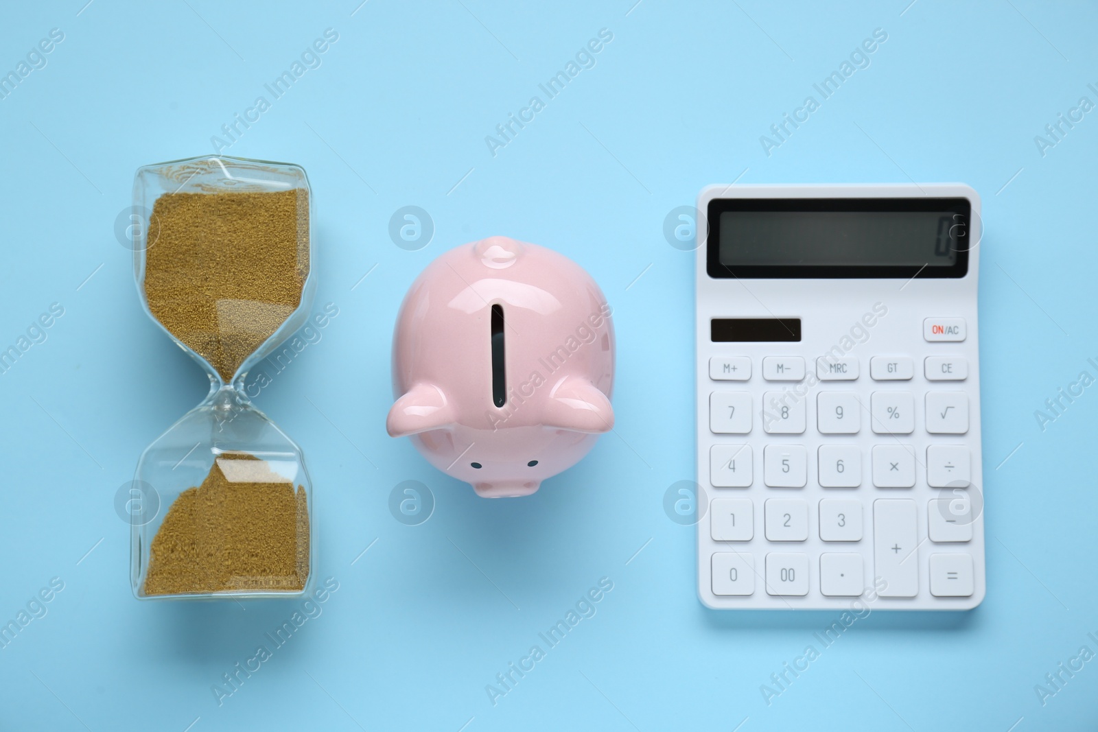 Photo of Piggy bank, hourglass and calculator on light blue background, flat lay