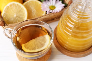 Photo of Cup of delicious tea with lemon and honey on white table, closeup