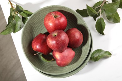 Fresh red apples and leaves on white table, flat lay