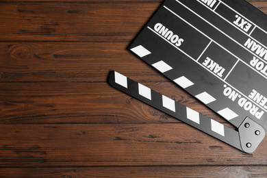 Photo of Clapperboard on wooden table, top view with space for text. Cinema production