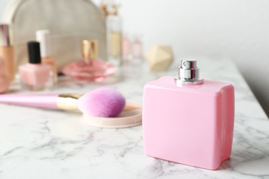 Bottle of perfume and cosmetics on marble table. Space for text