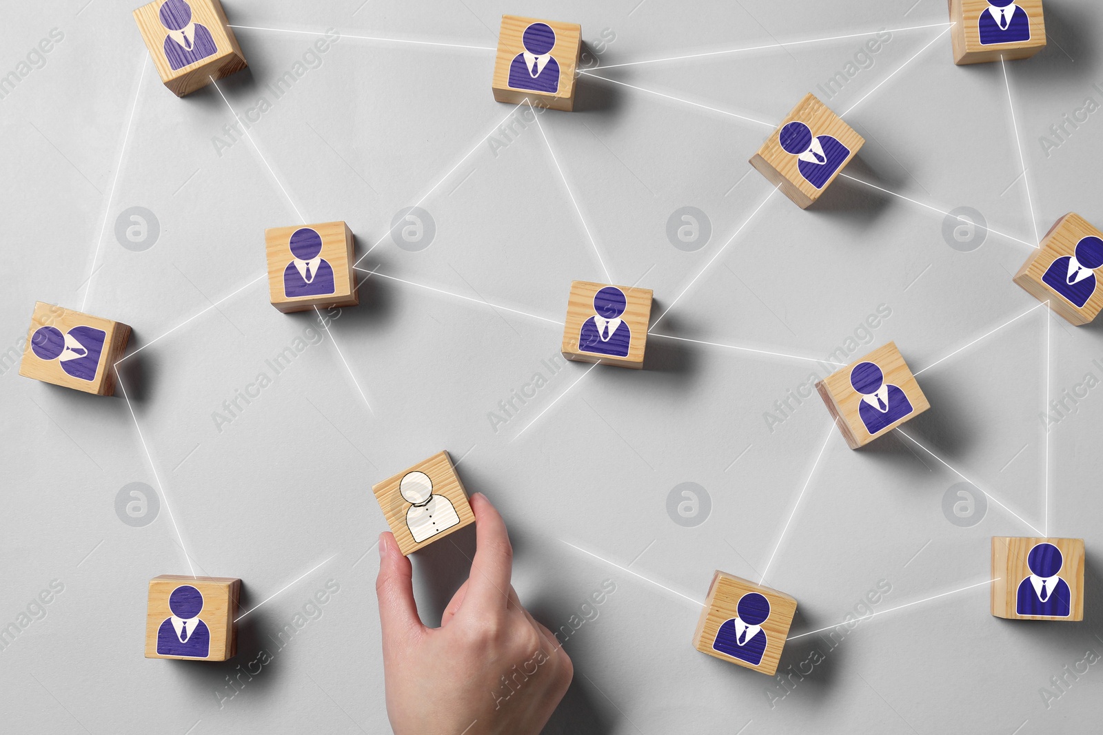 Image of Team management. Woman arranging wooden cubes with human icons linked together symbolizing company structure at grey table, top view