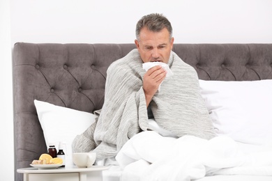 Man suffering from cough and cold in bed at home