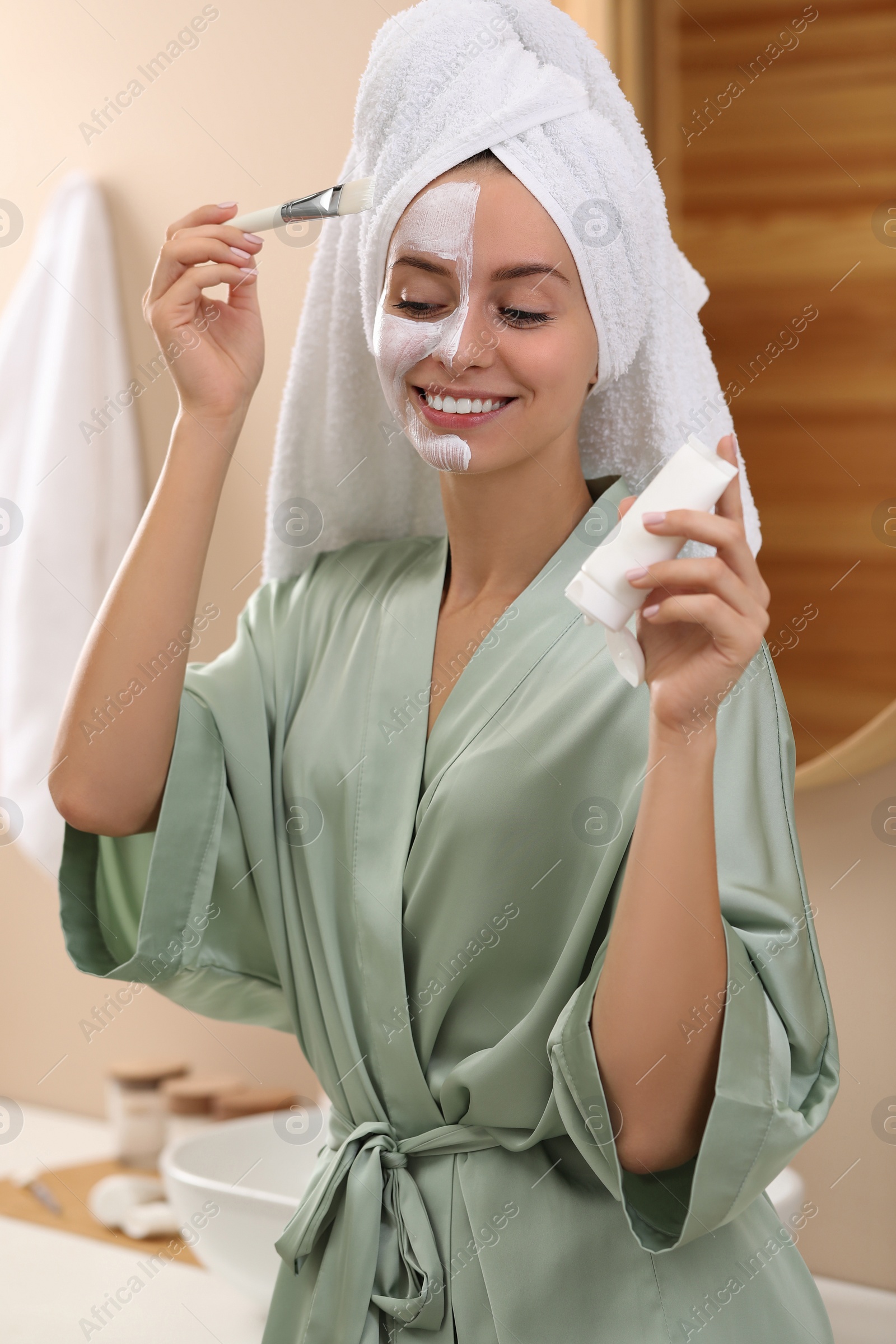 Photo of Woman applying face mask in bathroom. Spa treatments