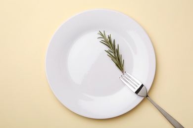 Photo of Plate with rosemary and fork on color background, flat lay