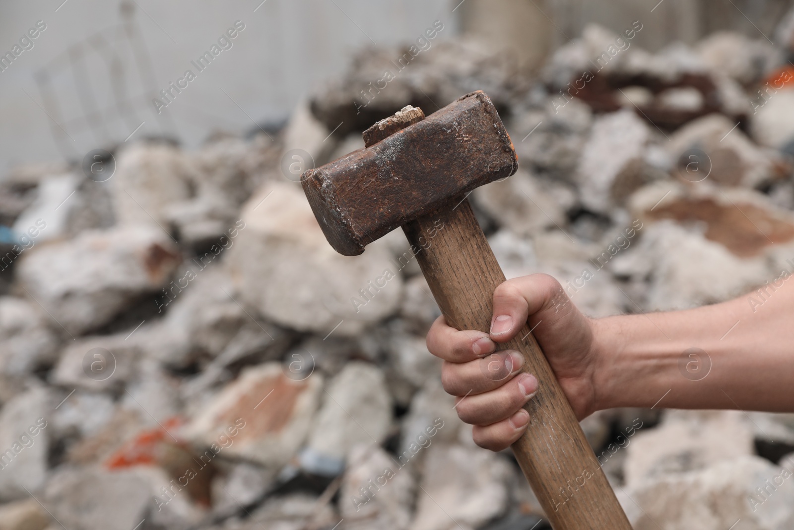 Photo of Man with sledgehammer near pile of stones outdoors, closeup. Space for text