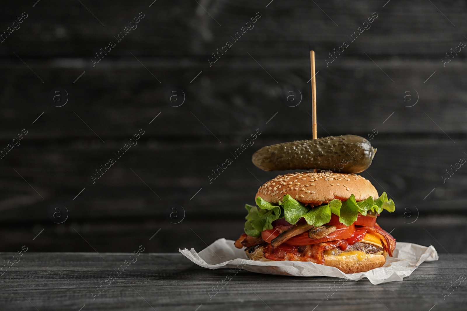 Photo of Tasty burger with bacon on wooden table. Space for text