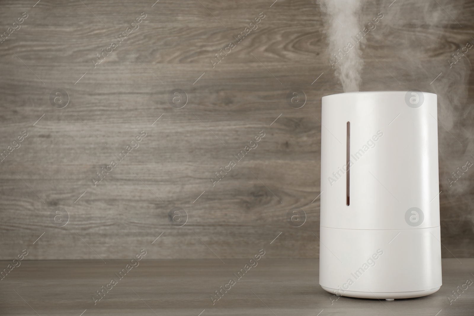 Photo of Modern air humidifier on wooden table. Space for text