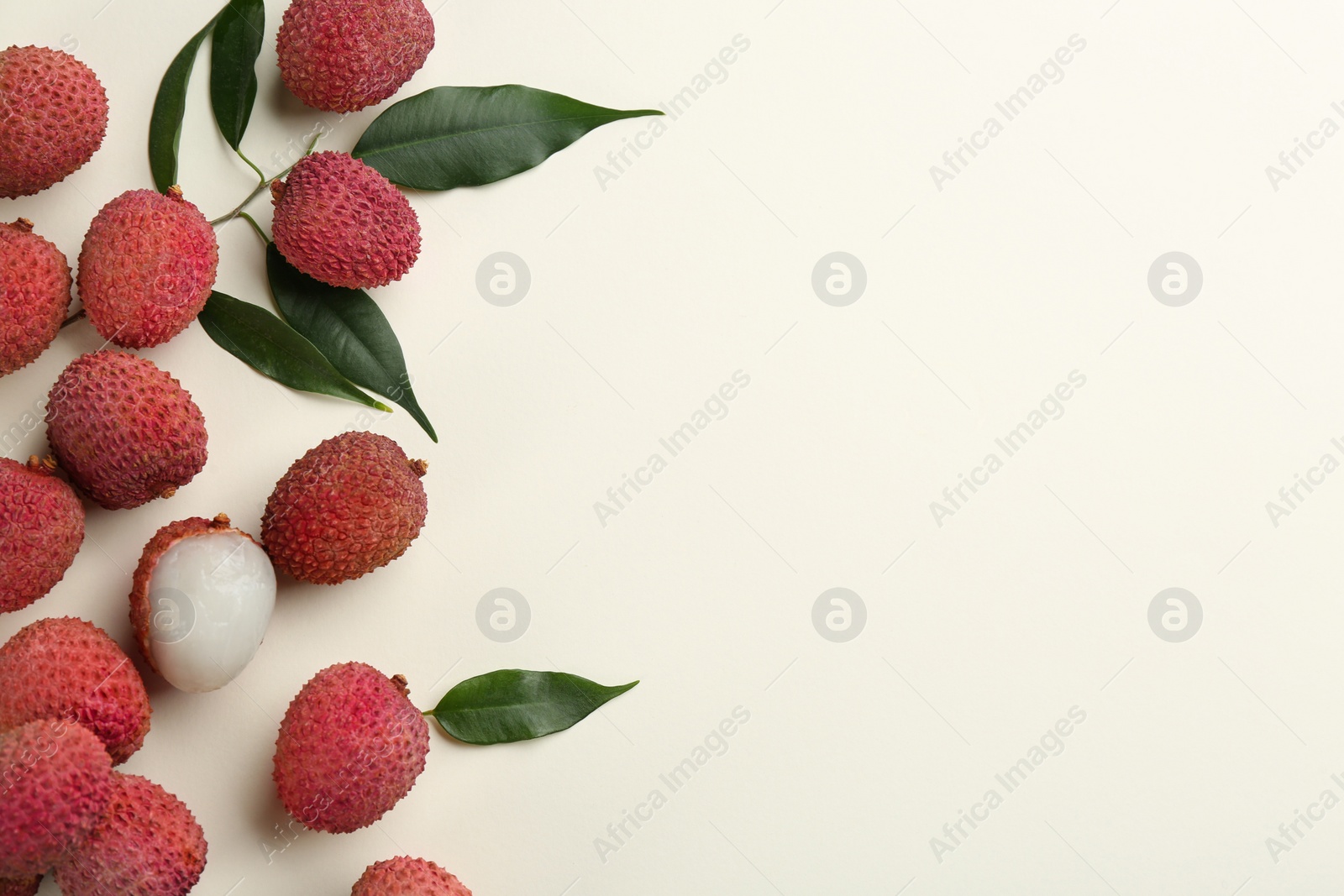 Photo of Fresh ripe lychees with leaves on beige background, flat lay. Space for text
