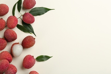 Photo of Fresh ripe lychees with leaves on beige background, flat lay. Space for text