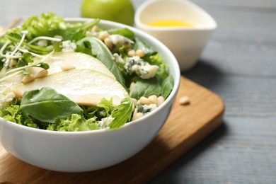 Photo of Fresh salad with pear on grey wooden table, closeup