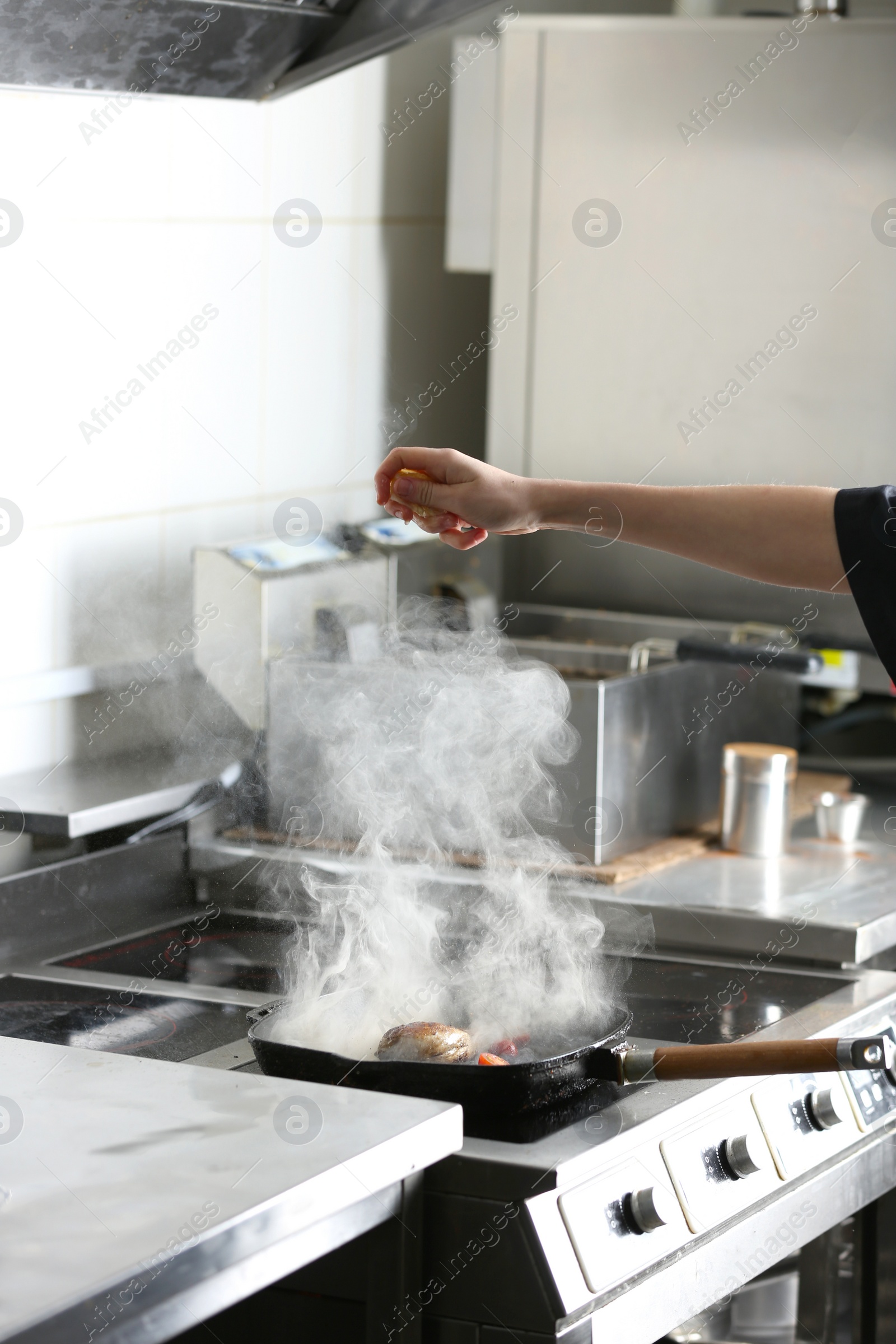 Photo of Female chef cooking meal on stove in restaurant kitchen, closeup