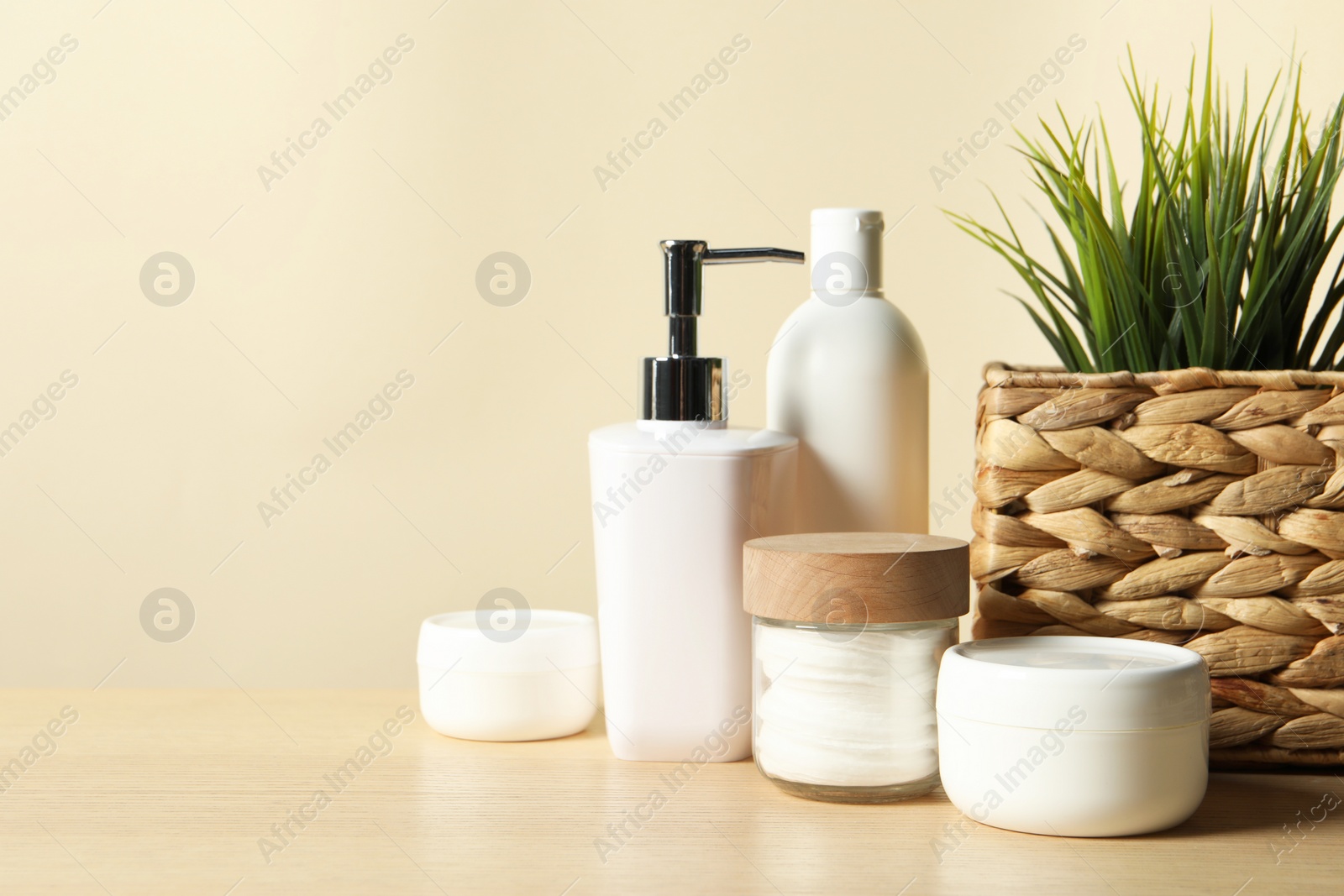 Photo of Different bath accessories and houseplant on wooden table against beige background, closeup. Space for text