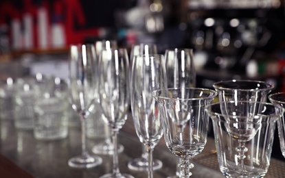 Photo of Different empty clean glasses on counter in bar