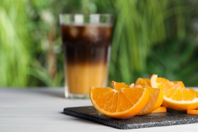 Photo of Tasty refreshing drink with coffee and orange juice on white table, focus on fruit slices