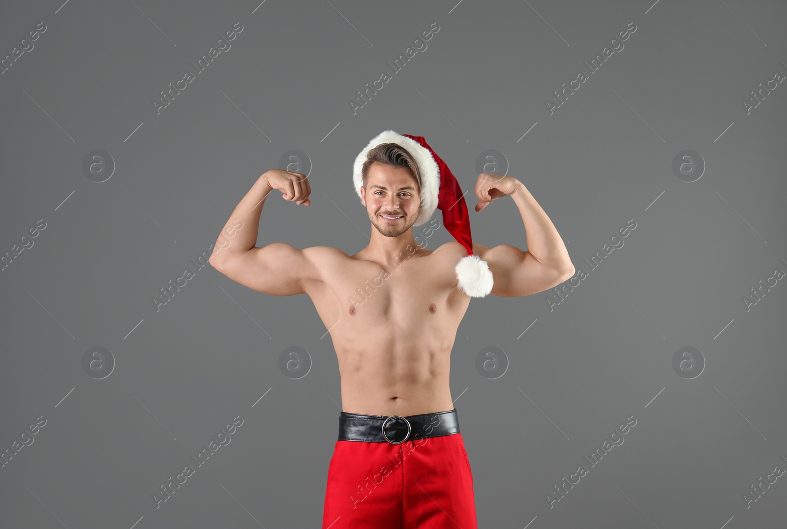 Photo of Shirtless young Santa Claus with sexy body on color background