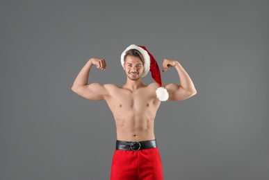 Photo of Shirtless young Santa Claus with sexy body on color background