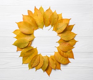 Frame of autumn leaves on white wooden table, top view. Space for text