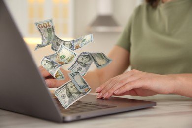 Image of Making money online. Closeup view of woman using laptop at table and flying dollars