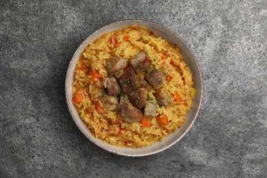 Delicious pilaf with meat on grey textured table, top view