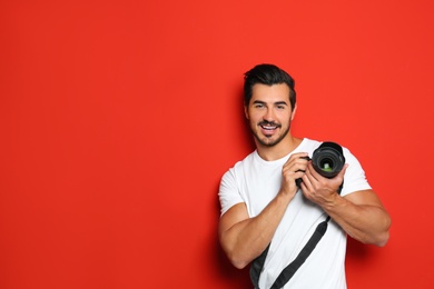 Photo of Young photographer with professional camera on red background. Space for text