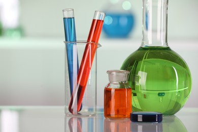 Laboratory analysis. Different glassware with liquids on white table against blurred background, closeup