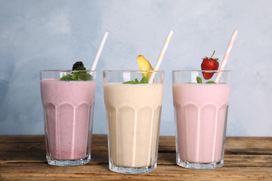 Photo of Different tasty milk shakes on wooden table