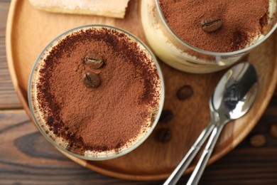 Photo of Delicious tiramisu in glasses served on wooden table, flat lay