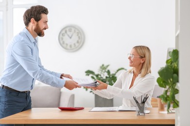 Photo of Man giving documents to colleague in office