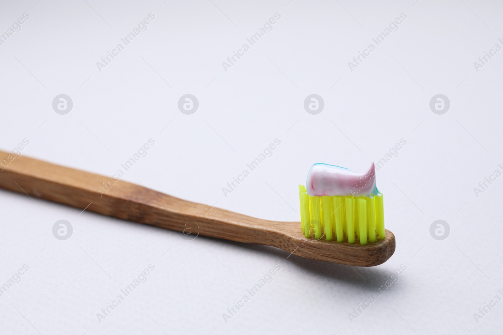 Photo of Wooden brush with toothpaste on white background, closeup