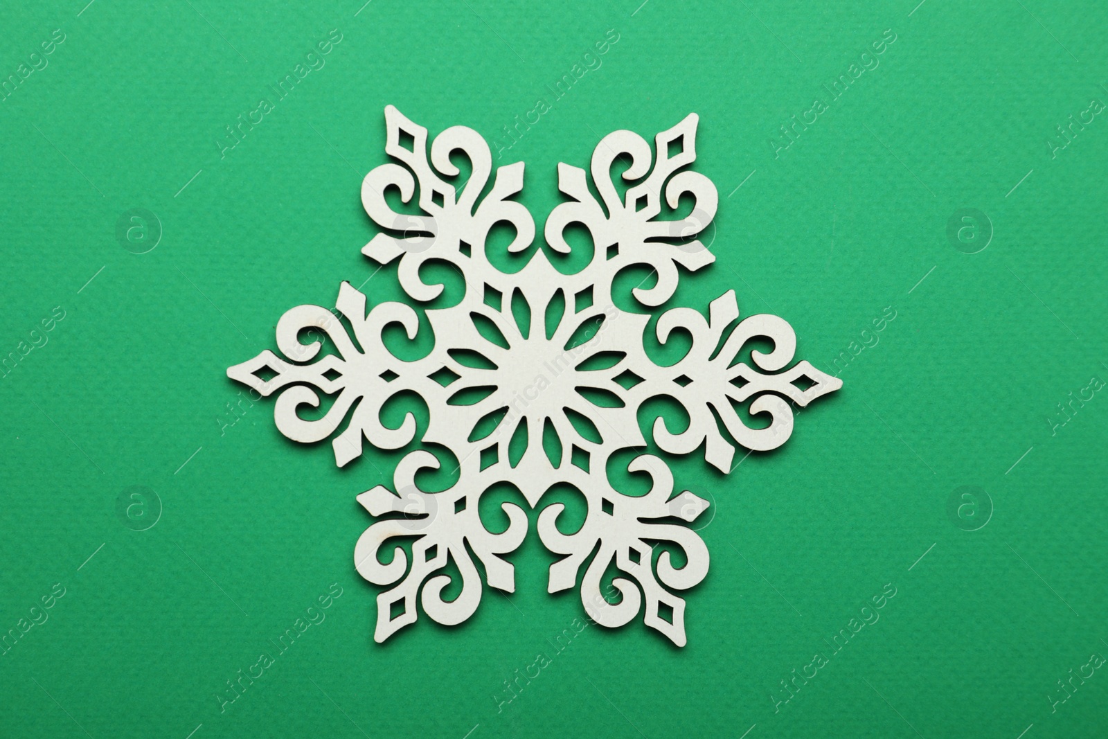 Photo of Beautiful decorative snowflake on green background, top view