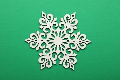 Beautiful decorative snowflake on green background, top view