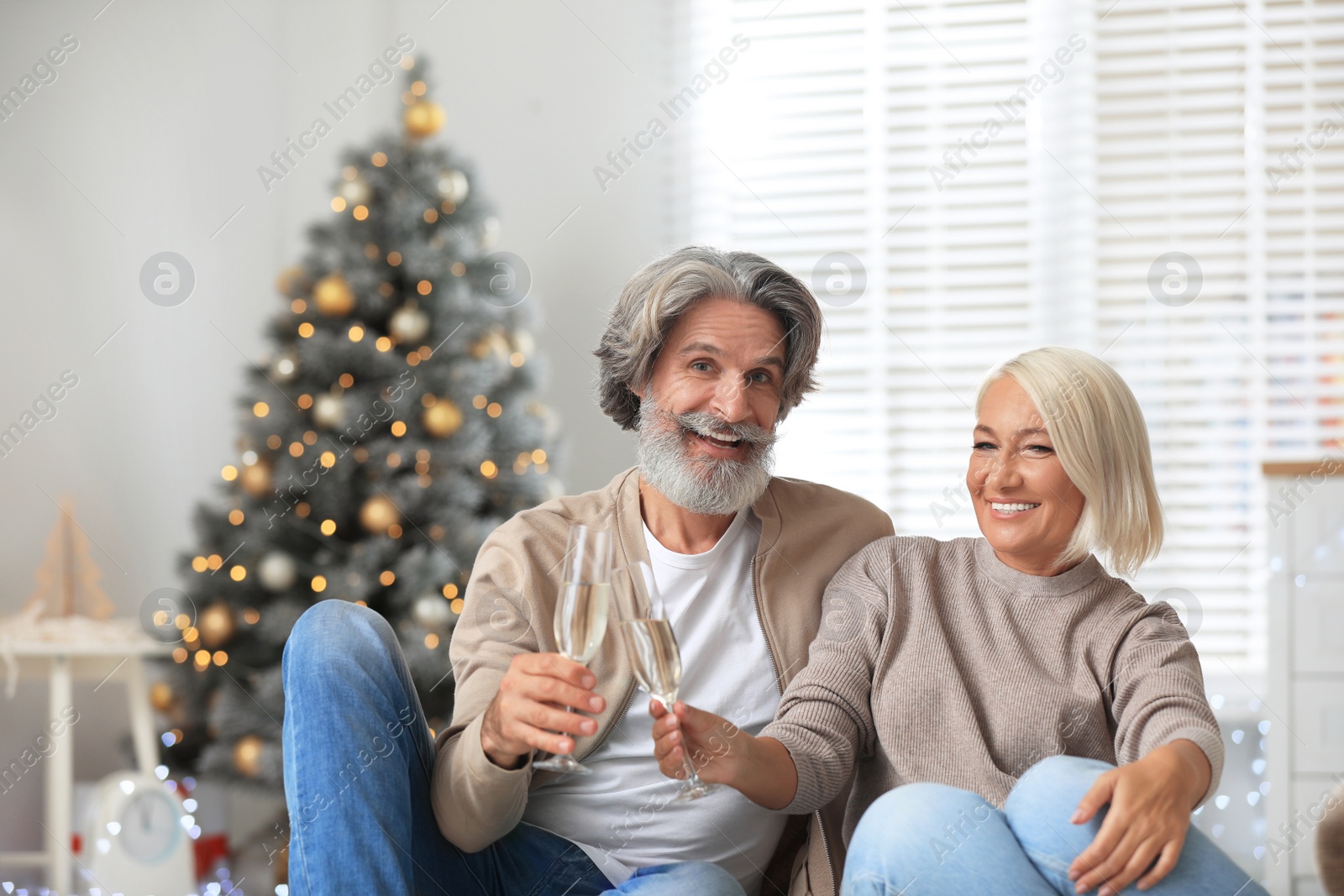 Photo of Happy mature couple with glasses of champagne celebrating Christmas at home