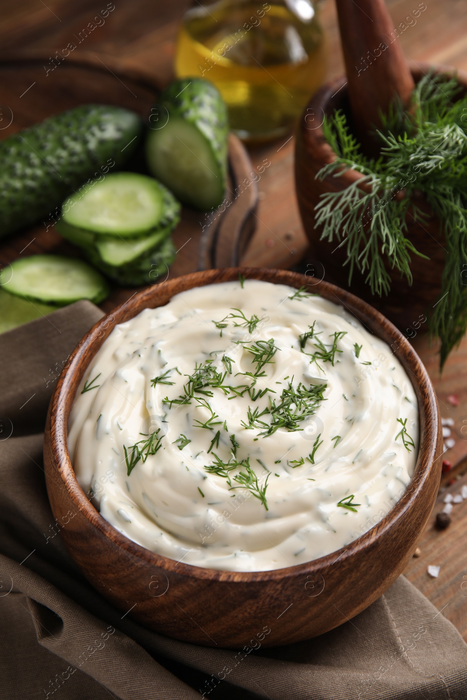 Photo of Tasty creamy dill sauce in bowl on wooden table