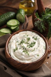 Tasty creamy dill sauce in bowl on wooden table