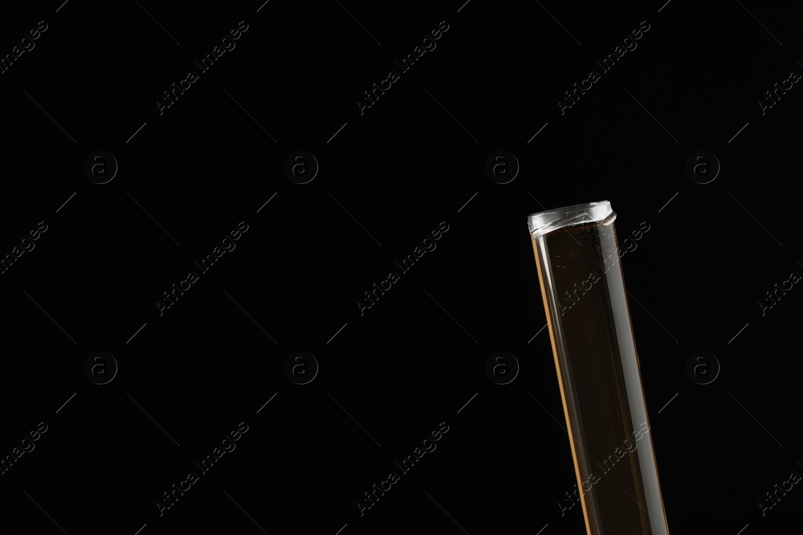 Photo of Test tube with brown liquid on black background, closeup. Space for text