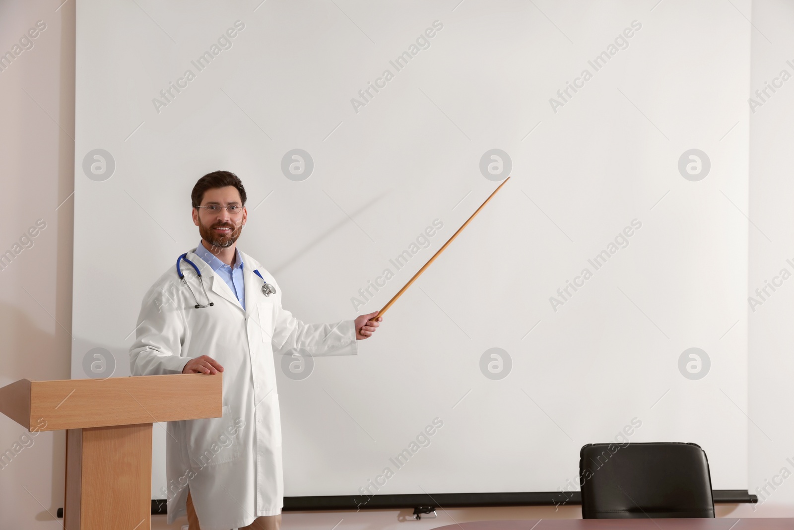 Photo of Doctor giving lecture in conference room with projection screen