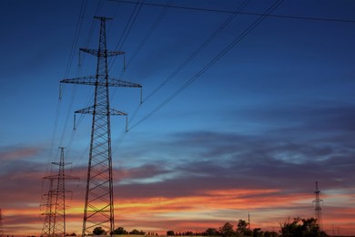 Photo of Telephone poles with cables at sunset outdoors