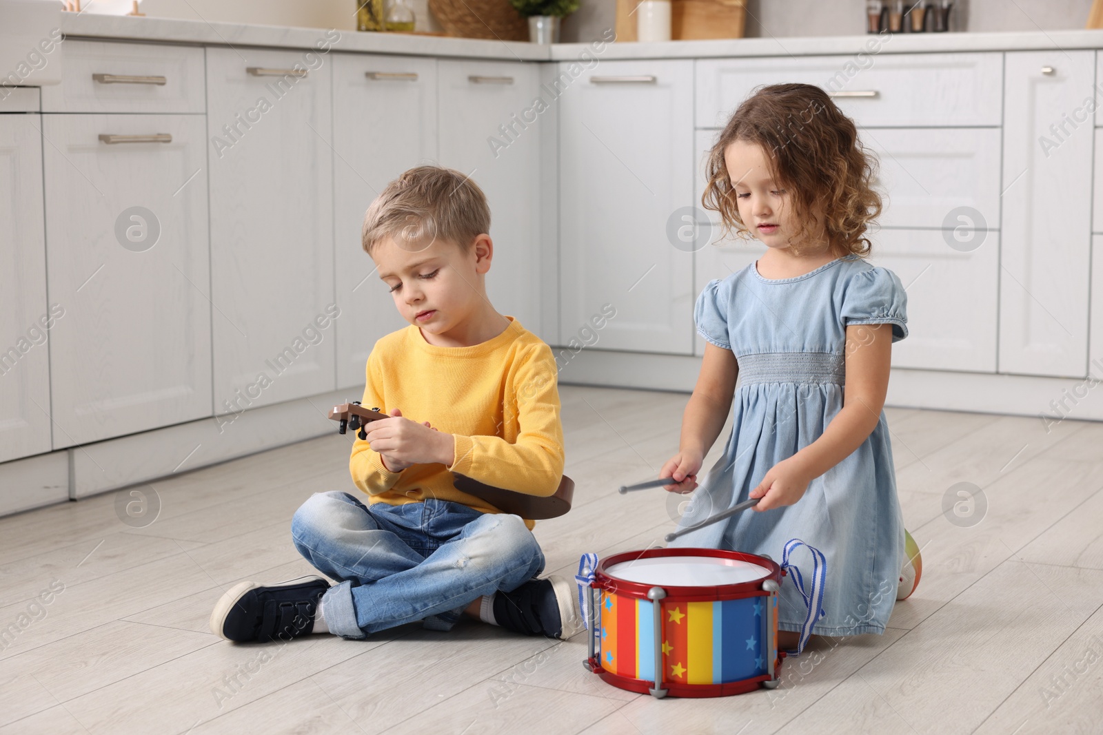 Photo of Little children playing toy musical instruments in kitchen