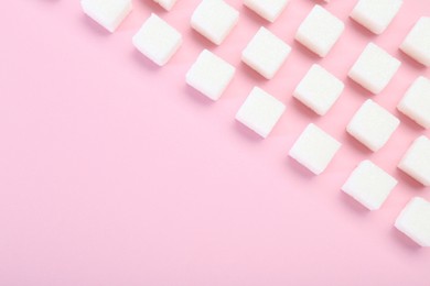 Photo of White sugar cubes on pink background, top view. Space for text