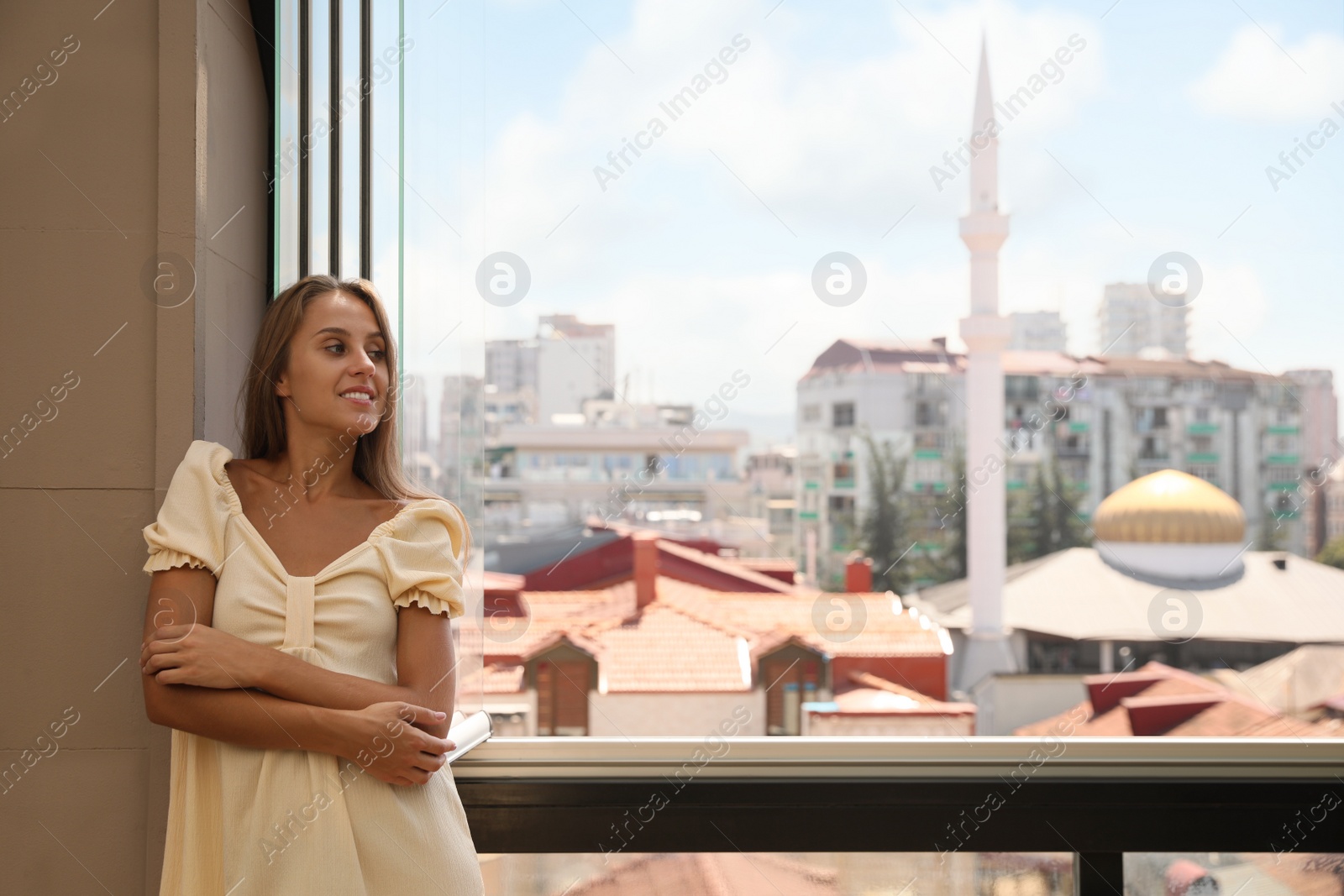 Photo of Beautiful young woman standing on balcony, space for text